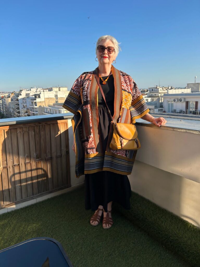 Image of artist Glenda Wood from Amanartis Studio at the Chapel Watford by Founder Amma Gyan of House of Amma and Amanartis, standing outside in the sun wearing an African Kimono by Jumandi Fabrics at House of Amma - The Art of Living Harlequin Watford.